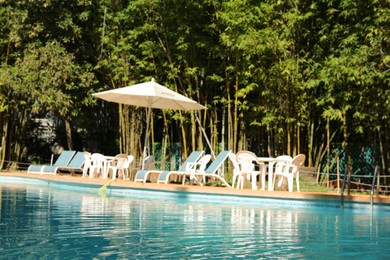 Pool with clean water, sunbeds and parasol outdoors