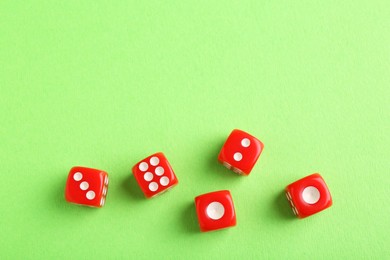 Many red game dices on green background, flat lay. Space for text