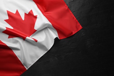 Photo of Flag of Canada on black table, top view. Space for text