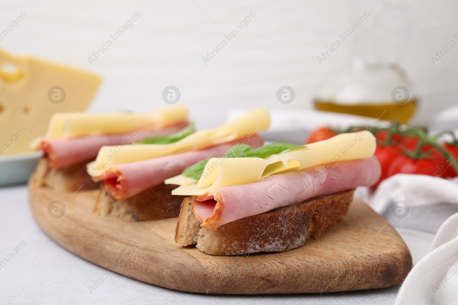 Photo of Delicious sandwiches with ham and cheese on light gray table, closeup