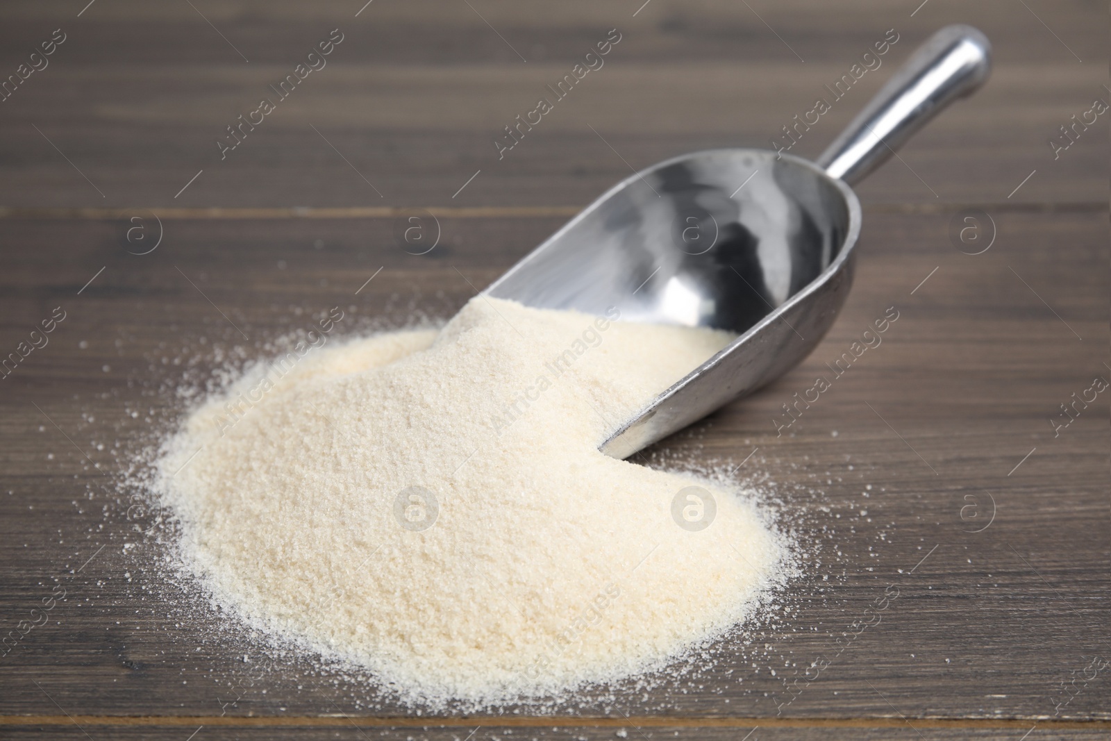 Photo of Pile of gelatin powder and scoop on wooden table