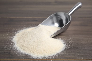 Photo of Pile of gelatin powder and scoop on wooden table