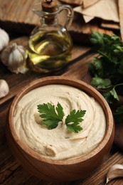 Delicious hummus with parsley on wooden table, closeup