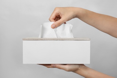 Photo of Woman taking paper tissue from holder on light background, closeup