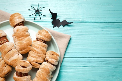 Photo of Spooky sausage mummies for Halloween party served on light blue wooden table, flat lay. Space for text