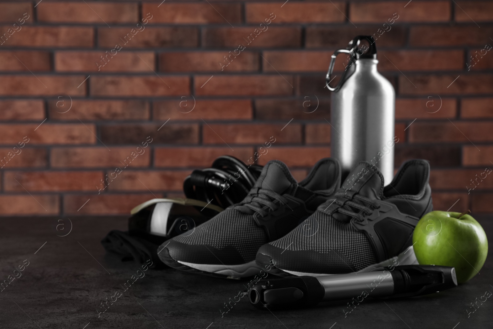 Photo of Different cycling accessories on black table against brick wall, space for text