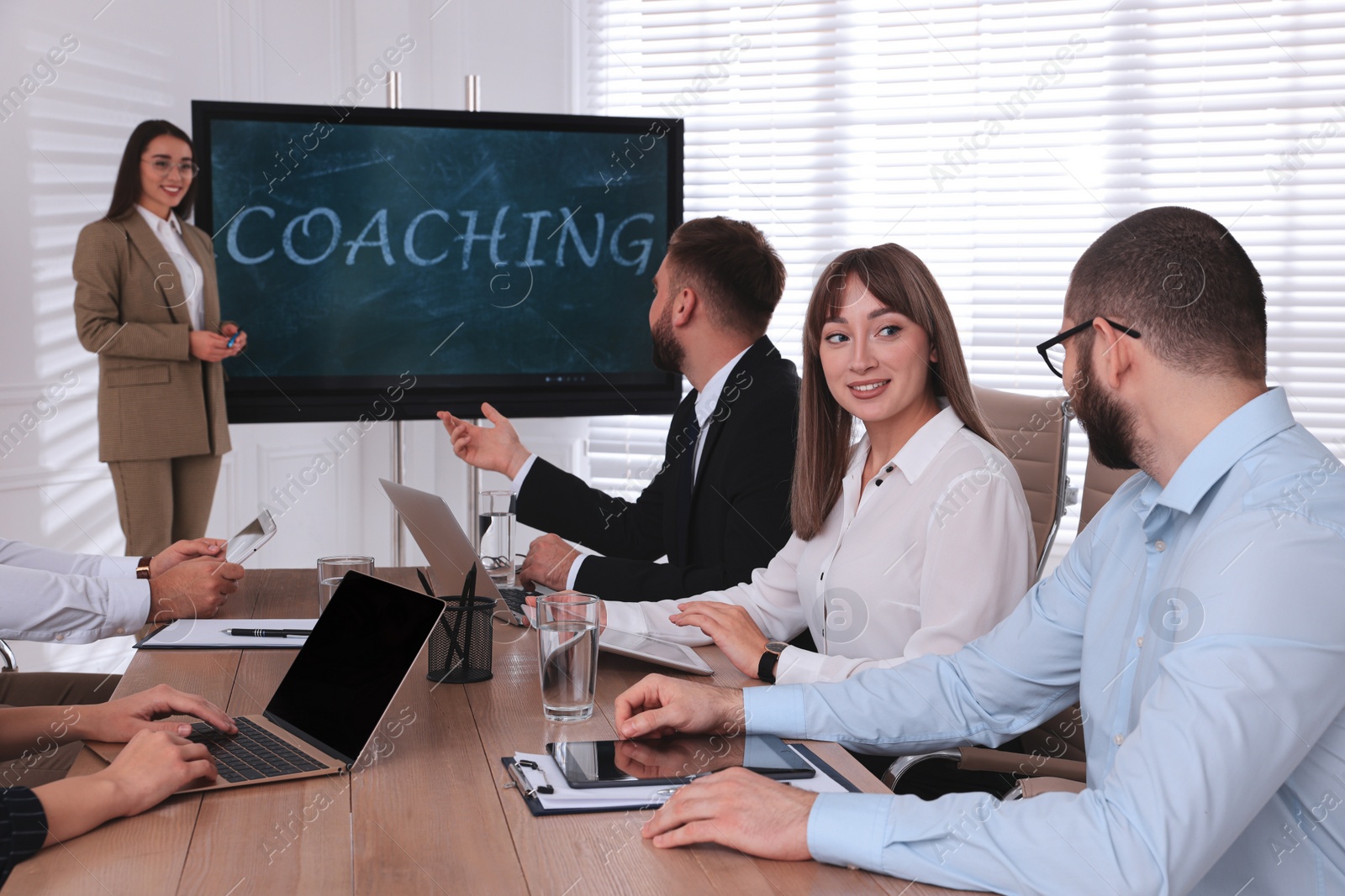 Photo of Business trainer near interactive board in meeting room during presentation, focus on colleagues