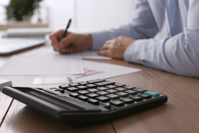 Tax accountant working in office, focus on calculator