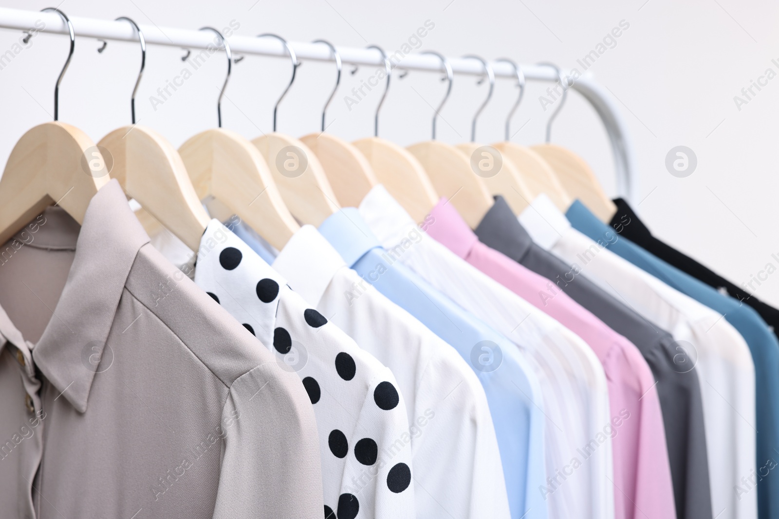 Photo of Dry-cleaning service. Many different clothes hanging on rack against white background, closeup