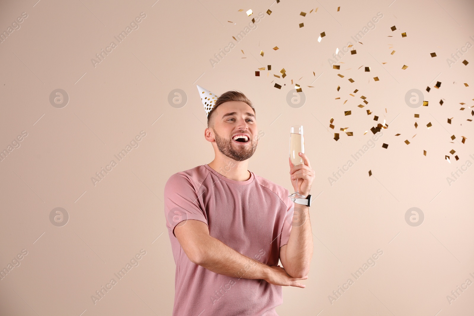 Photo of Portrait of happy man with champagne in glass and confetti on color background