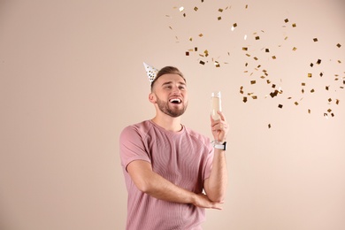 Portrait of happy man with champagne in glass and confetti on color background