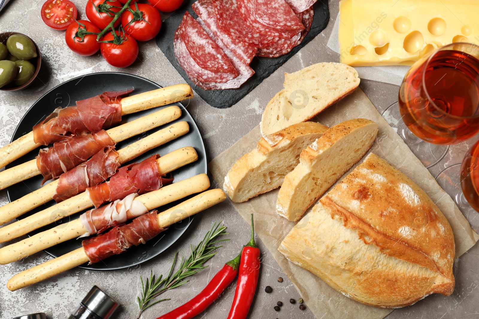 Photo of Tasty prosciutto with bread served on brown marble table, flat lay