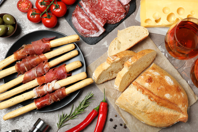 Tasty prosciutto with bread served on brown marble table, flat lay