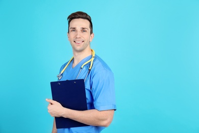 Portrait of medical assistant with stethoscope and clipboard on color background. Space for text