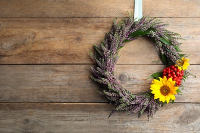 Photo of Beautiful autumnal wreath with heather flowers hanging on wooden background. Space for text