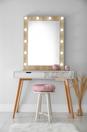Photo of Stylish mirror with lamps near light wall in room