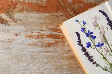 Photo of Open book with beautiful dried flowers on wooden table, top view. Space for text