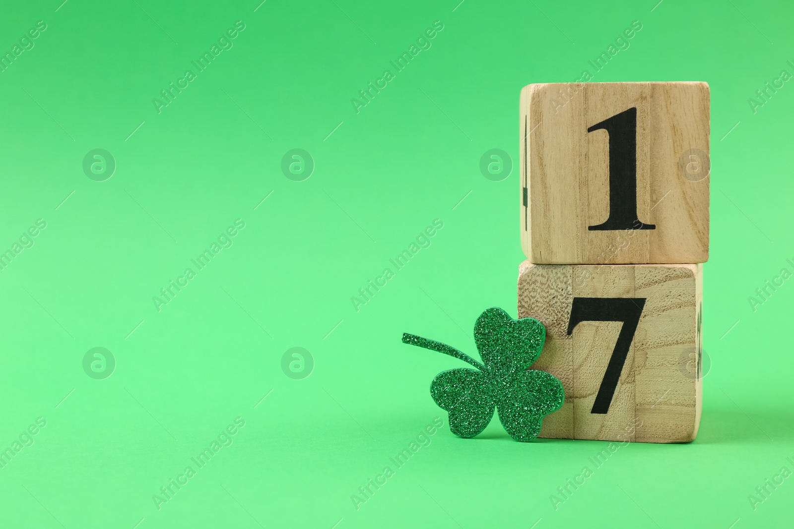 Photo of St. Patrick's day - 17th of March. Block calendar and decorative clover leaf on green background. Space for text