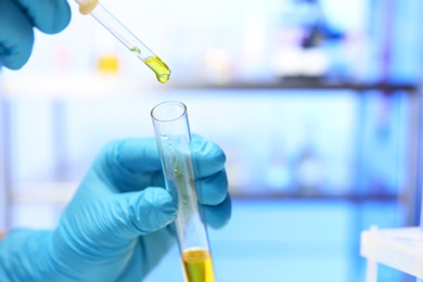 Laboratory assistant dripping urine sample from pipette into test tube, closeup with space for text. Medical analysis