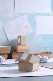 Photo of Creating packaging design. Drawings and boxes on blue textured table, closeup