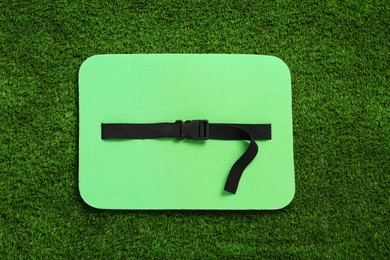 Bright foam seat mat for tourist on green grass, top view