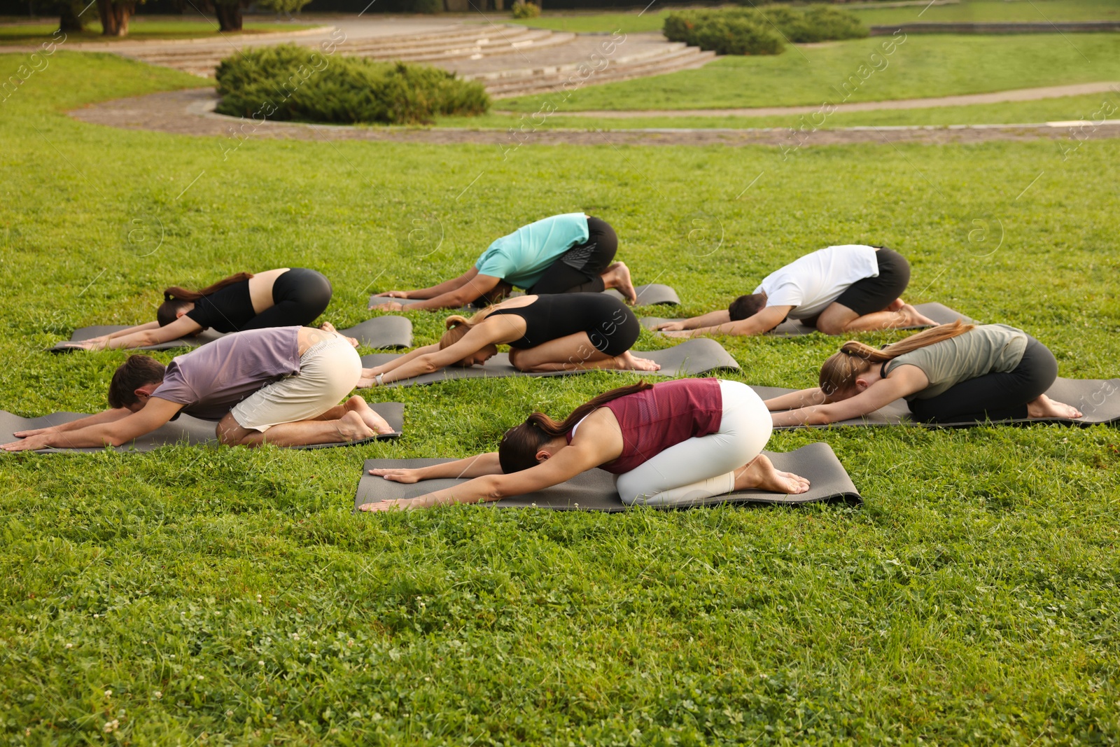 Photo of Group of people practicing yoga on mats outdoors