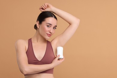 Photo of Beautiful woman applying deodorant on beige background, space for text