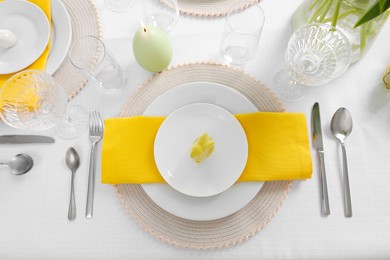 Photo of Festive table setting with cutlery, plate and bunny figure, flat lay. Easter celebration