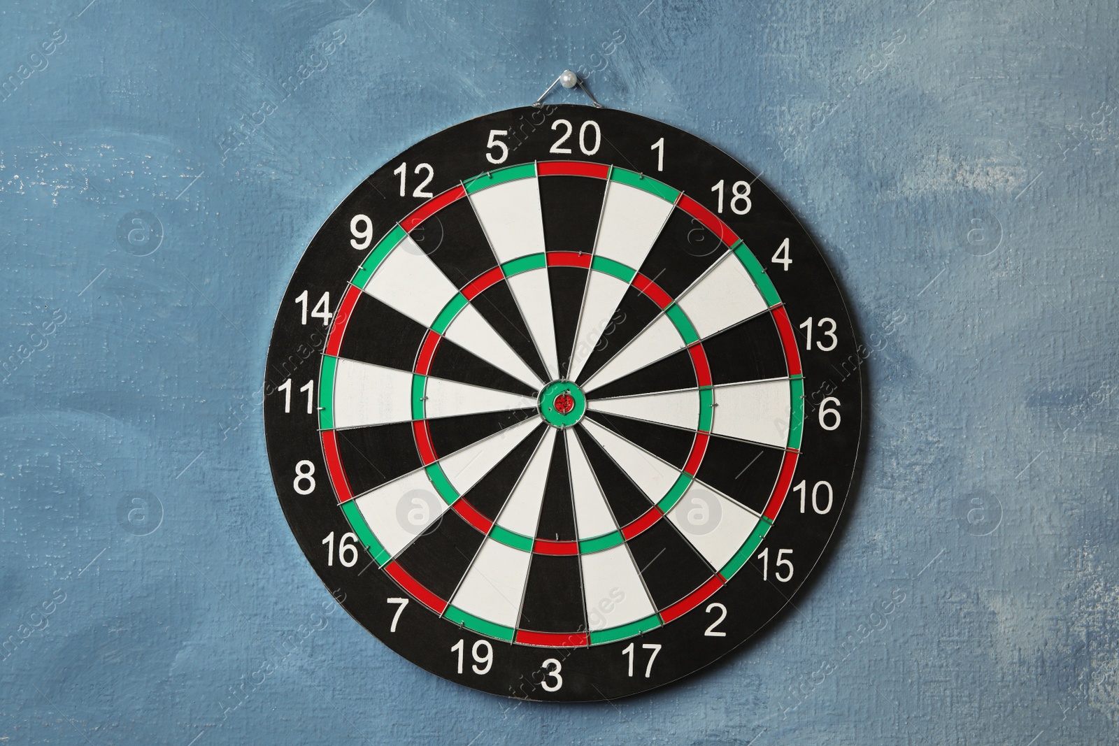 Photo of Dart board hanging on blue textured wall