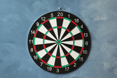 Photo of Dart board hanging on blue textured wall