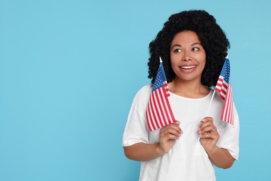 4th of July - Independence Day of USA. Happy woman with American flags on light blue background, space for text