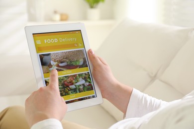 Man using tablet for ordering food online at home, closeup. Delivery service
