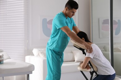 Photo of Woman receiving massage in modern chair indoors