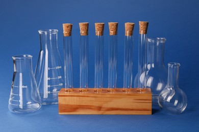 Photo of Different laboratory flasks and test tubes on blue background