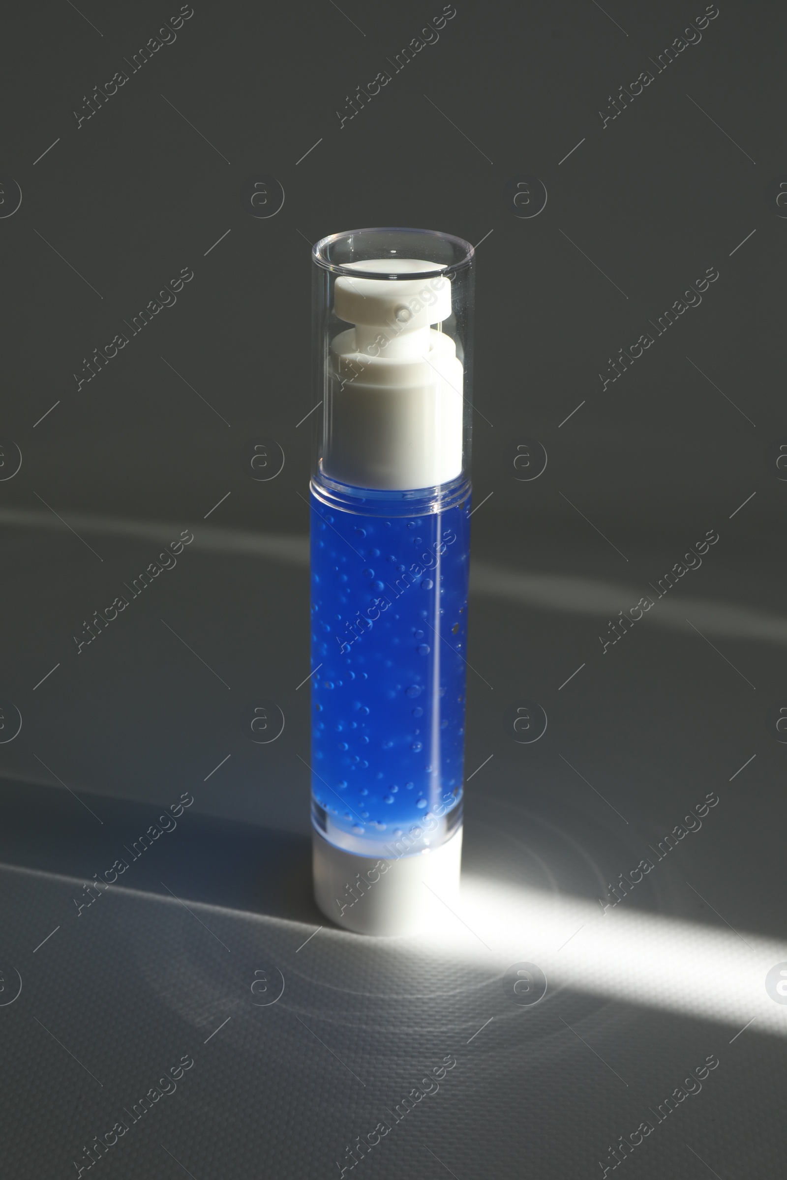Photo of Bottle of cosmetic product on grey table