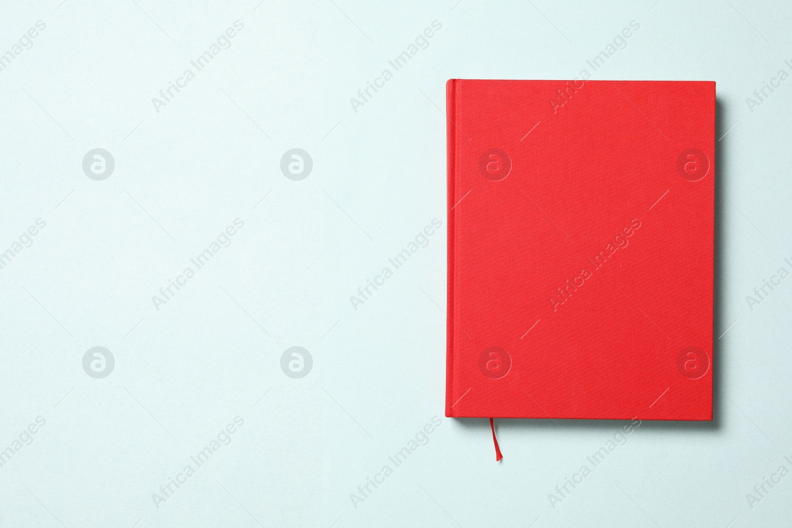 Photo of Book with red cover on light blue background, top view. Space for text