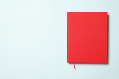 Photo of Book with red cover on light blue background, top view. Space for text