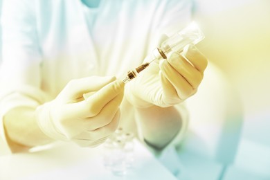 Image of Doctor filling syringe with medication from vial, closeup