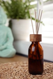 Photo of Air reed freshener and wicker mat on table indoors