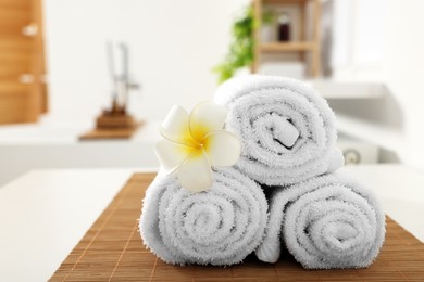 Photo of Rolled towels on white table in bathroom. Space for text