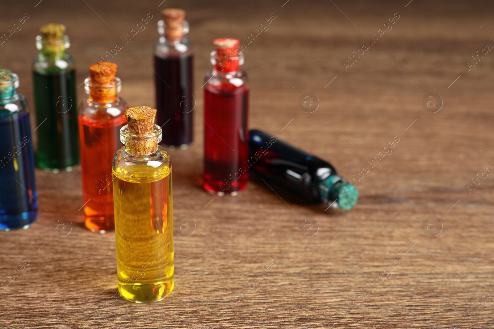 Photo of Bottles with different food coloring on wooden background, space for text