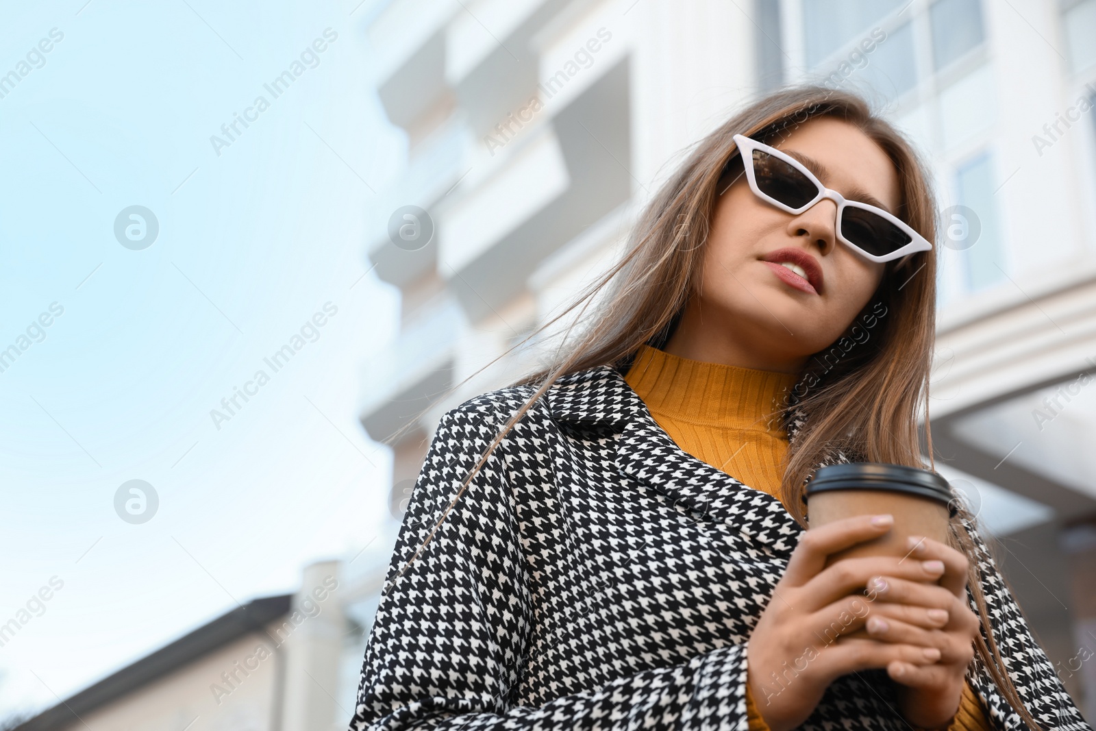 Photo of Young woman with cup of coffee on city street in morning