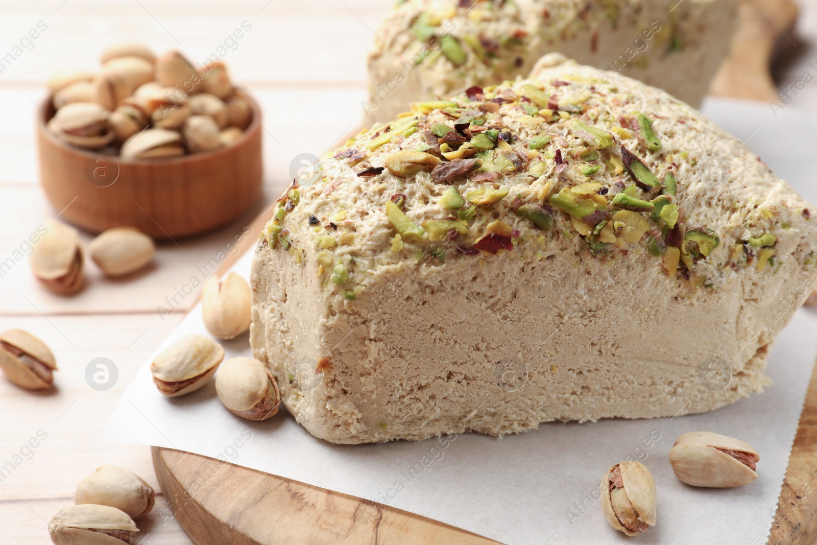 Photo of Tasty halva with pistachios on table, closeup