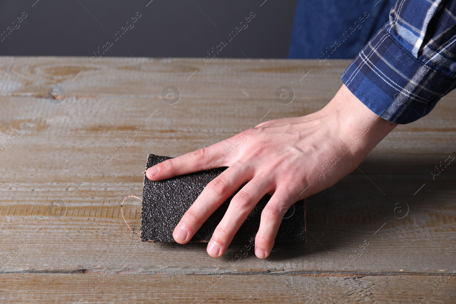 Photo of Man polishing wooden table with sandpaper, closeup