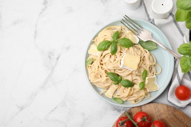 Delicious pasta with brie cheese, basil and fork on white marble table, flat lay. Space for text
