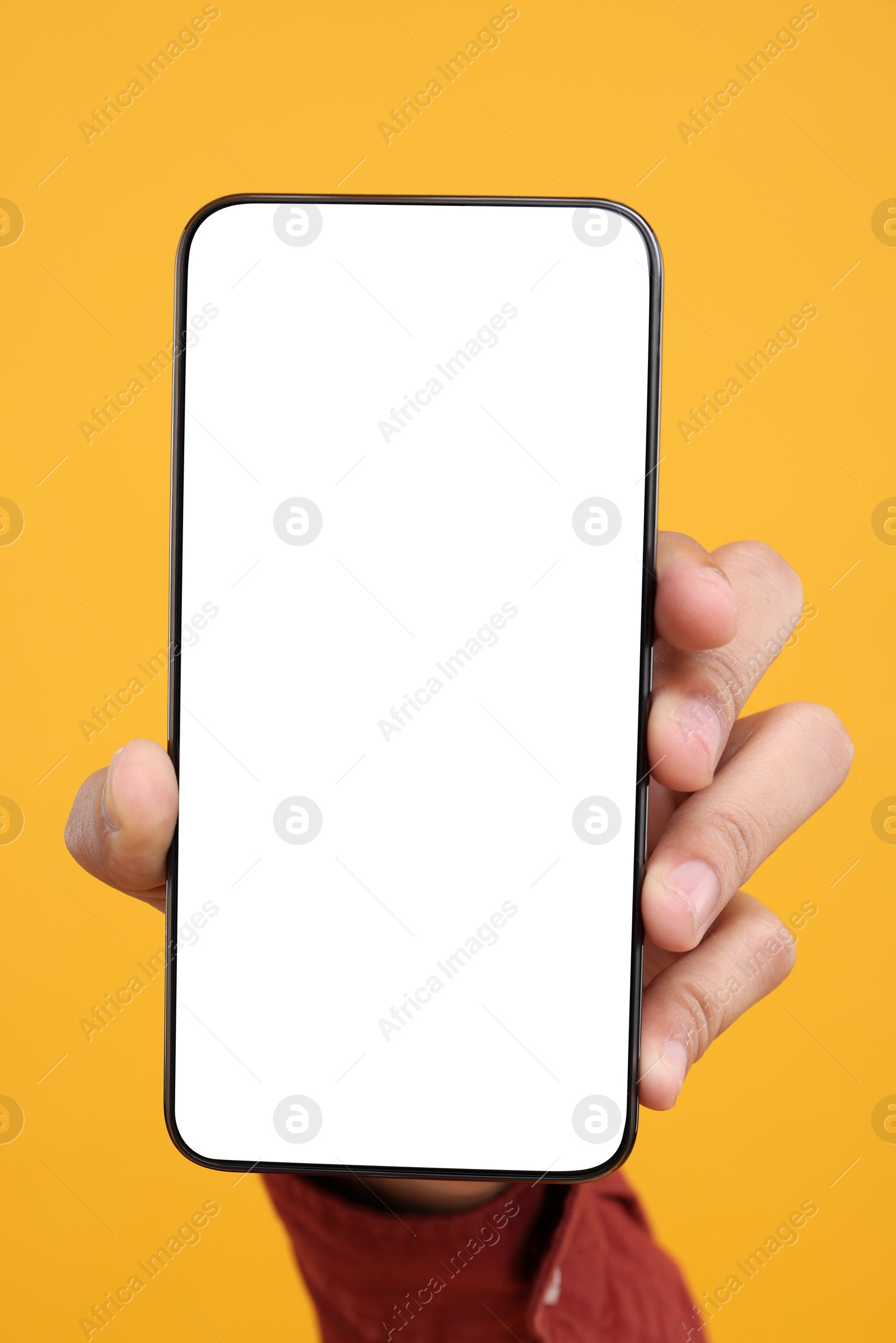 Photo of Man holding smartphone with blank screen on yellow background, closeup