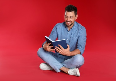 Photo of Handsome man reading book on red background