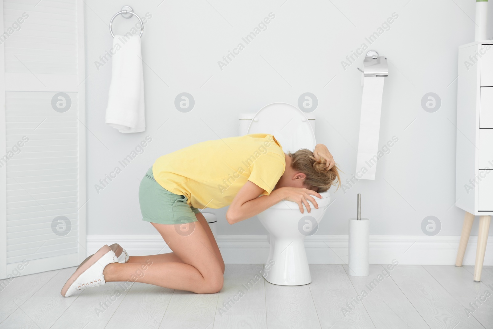 Photo of Young woman vomiting in toilet bowl at home