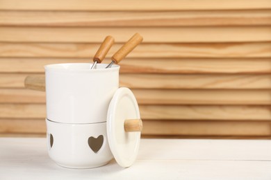 Photo of Fondue set on white wooden table, space for text