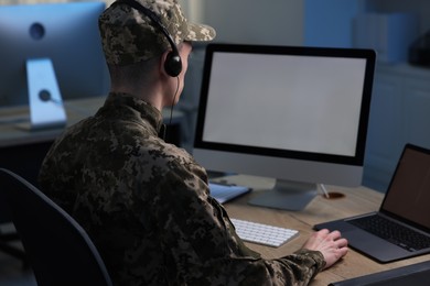 Photo of Military service. Soldier in headphones working at table in office at night